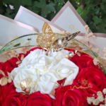 Détail papillon doré sur composition florale artisanale