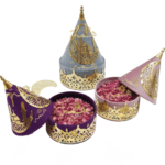 Trois coffrets cadeaux Aïd Moubarak en velours (violet, gris, rose) avec décorations dorées calligraphiées.