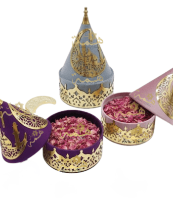 Trois coffrets cadeaux Aïd Moubarak en velours (violet, gris, rose) avec décorations dorées calligraphiées.