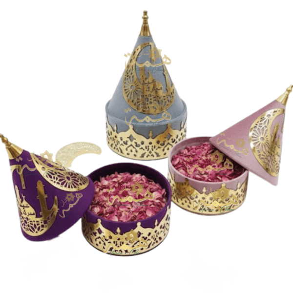 Trois coffrets cadeaux Aïd Moubarak en velours (violet, gris, rose) avec décorations dorées calligraphiées.