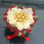 Close-up de roses blanches éternelles entourant des chocolats Ferrero Rocher dorés.