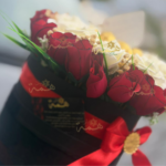 Boîte en forme de cœur noire avec ruban satiné rouge et logo doré.